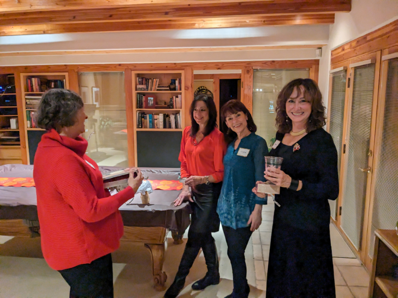 Photo of four women standing by a table and talking
